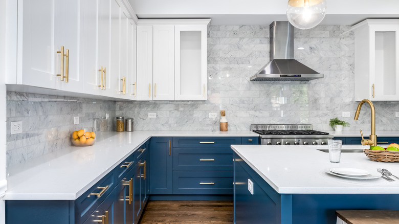 Modern kitchen with white countertops and white upper cabinets with blue lower cabinets.