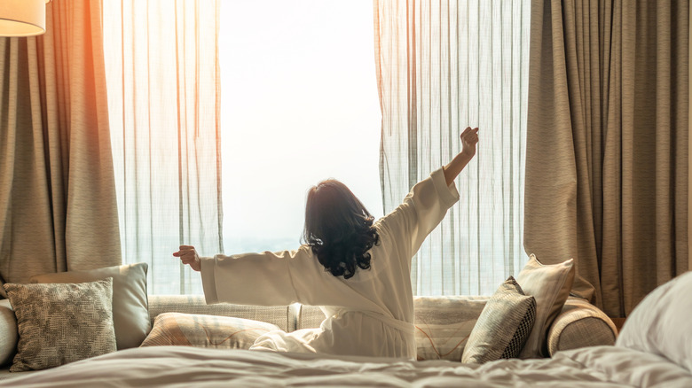 Woman sitting on bed stretching in morning