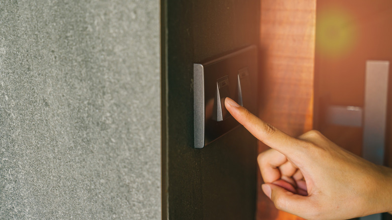 A person uses a modern light switch with a screwless cover