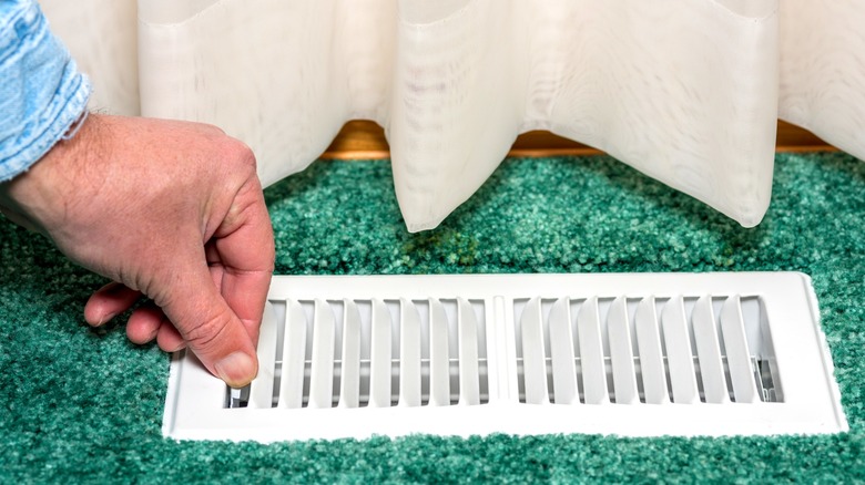 Person opening floor air register