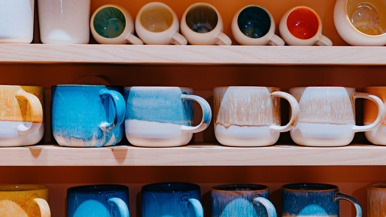 Colorful coffee mugs stored on shelves.