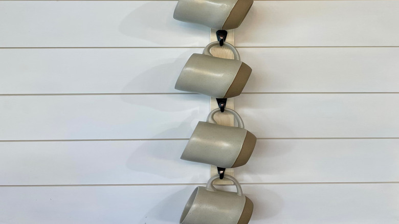 Mugs hanging from vertical wall-mounted rack.