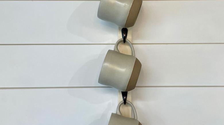Mugs hanging from vertical wall-mounted rack.