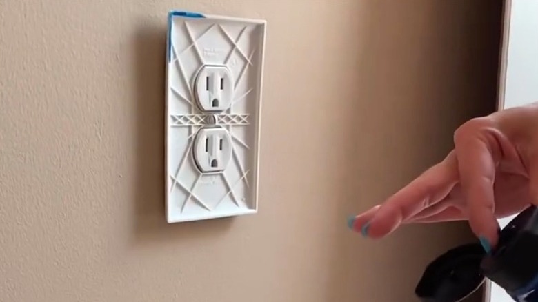 Person putting paint around outlet cover to mark cut points for beadboard