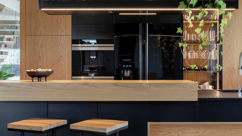 Stylish modern kitchen with a short wooden divider wall at the end of the kitchen island closest to the stools
