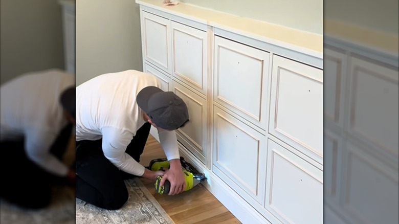 Person adding baseboard wood trim to DIY IKEA shoe cabinet with built-in look