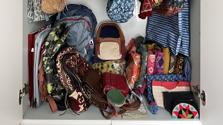 messy pile of purses and bags in a small cabinet