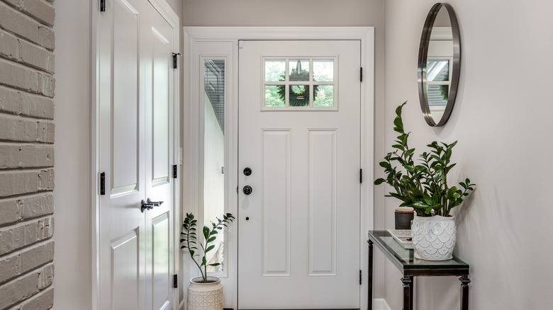 White entryway with small table and plants