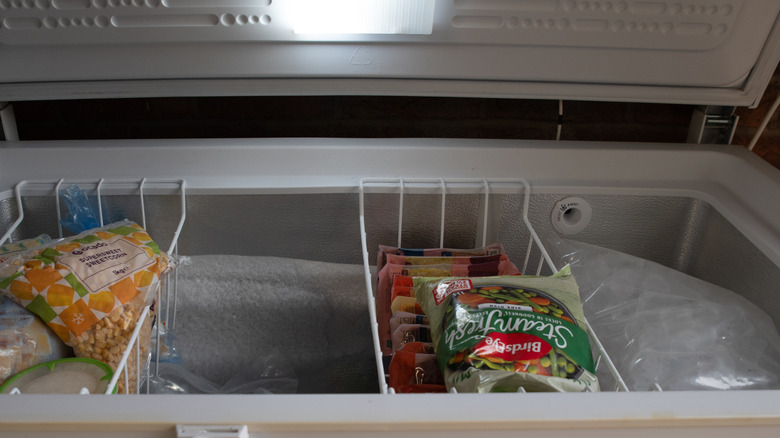 The inside of a home freezer with packets of frozen vegetables visible
