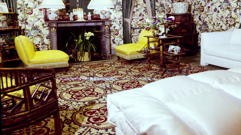 Bright yellow chairs with gold trim in an ornate room with heavily patterned wallpaper and carpet.