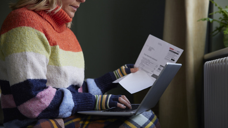 Woman in sweater pay electric bill on laptop