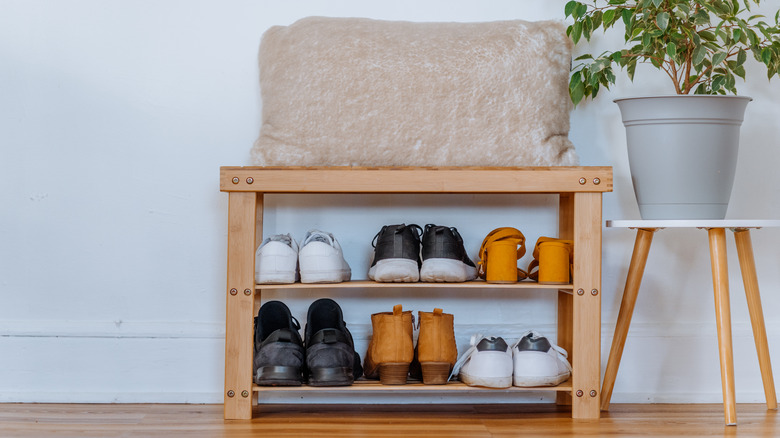 Wooden two-tier shoe rack filled with shoes