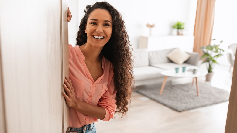 woman smiling and opening door