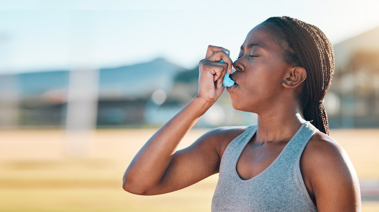 A woman struggling to breathe uses an inhaler