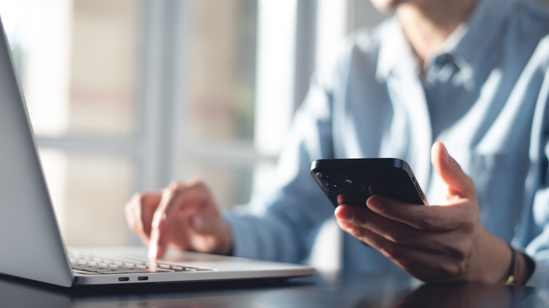 A person uses their laptop and cell phone at home