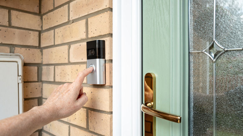 A person uses a Ring home security doorbell with camera