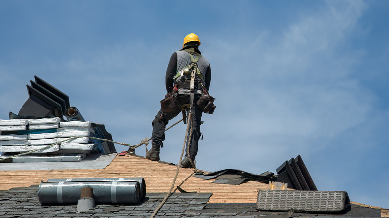 Roofer standing on roof that is being reshingled