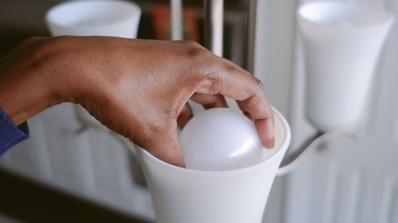 Woman taking lightbulb out of fixture