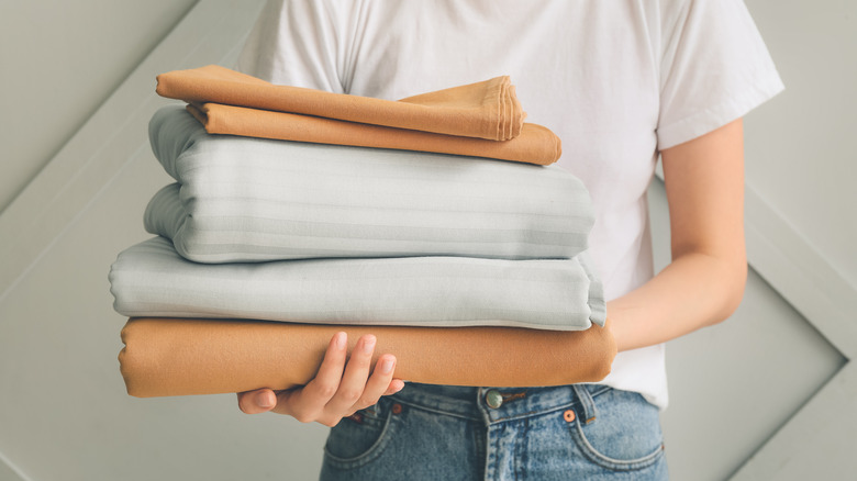 Person holding folded bed sheets