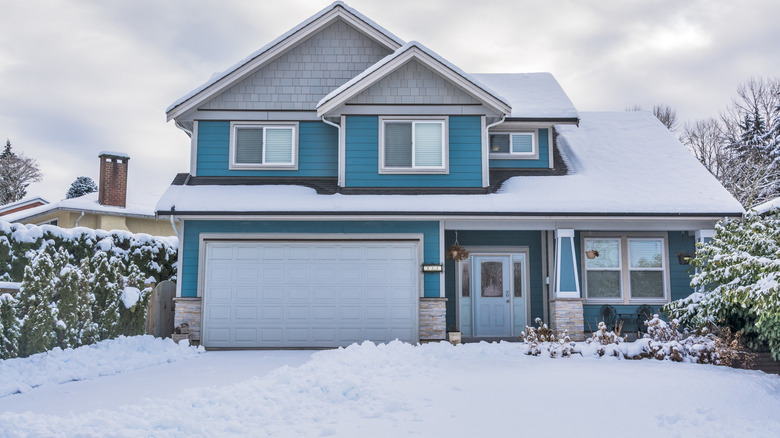 blue two story house with snow covering yard and driveway