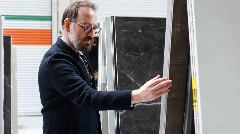 Man shopping for countertop materials looking at sheets of marble and quartz.