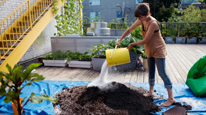 Young woman with a yellow bucket mixing soil ingredients