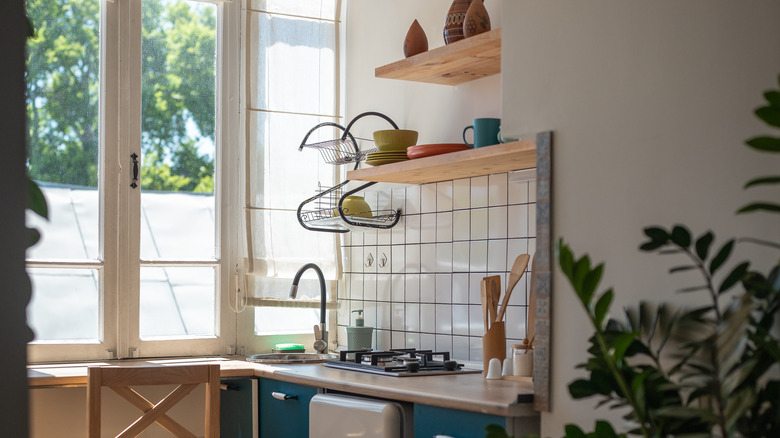 tiny kitchen by window with minimal storage and two floating shelves
