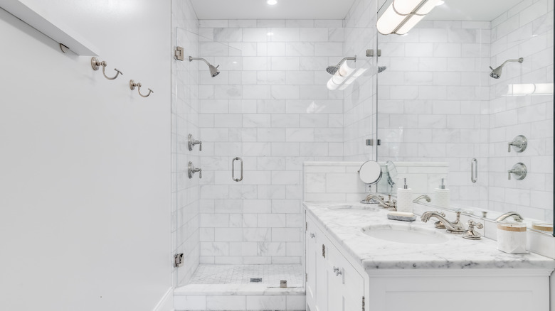 White bathroom with a shower that has two shower heads