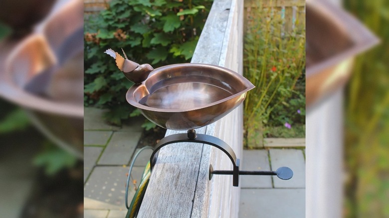A Charlton Home bird bath attached to a wooden wall.
