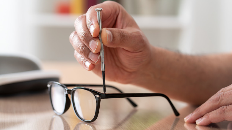 A person using a precision screwdriver to repair a pair of eyeglasses