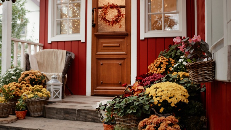 A front porch displays many baskets and pots of autumn flowers.