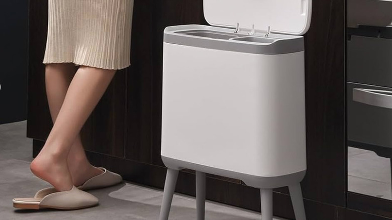 woman standing beside a white decorative trash can