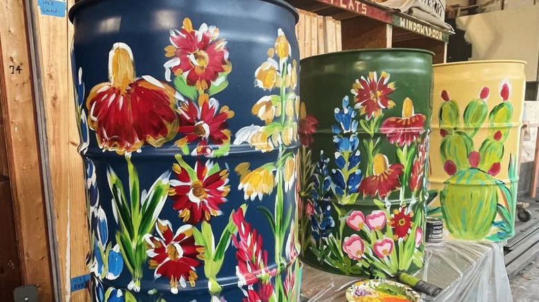 three hand-painted trash cans with flowers and cacti