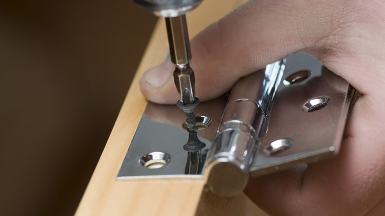 Closeup of someone adding a hinge to a door