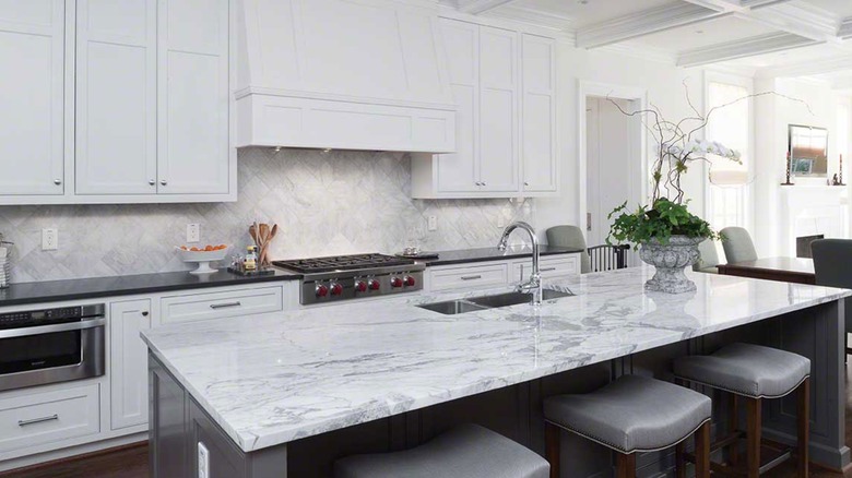 interior of all white kitchen with marble island countertop
