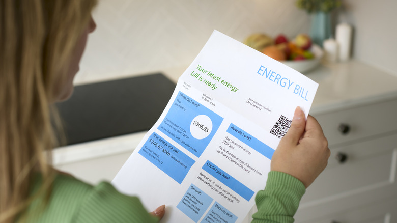 A woman holds a paper copy of an energy bill
