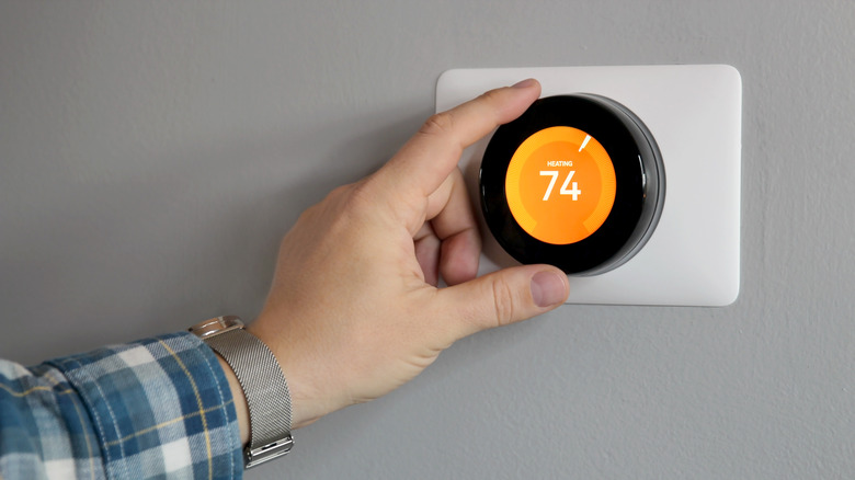 A person adjusts the heat on a thermostat