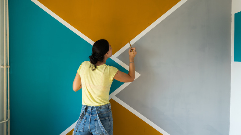 A person painting a geometric design on a wall