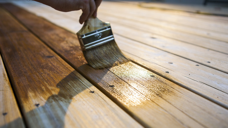 paintbrush applying stain to wood boards