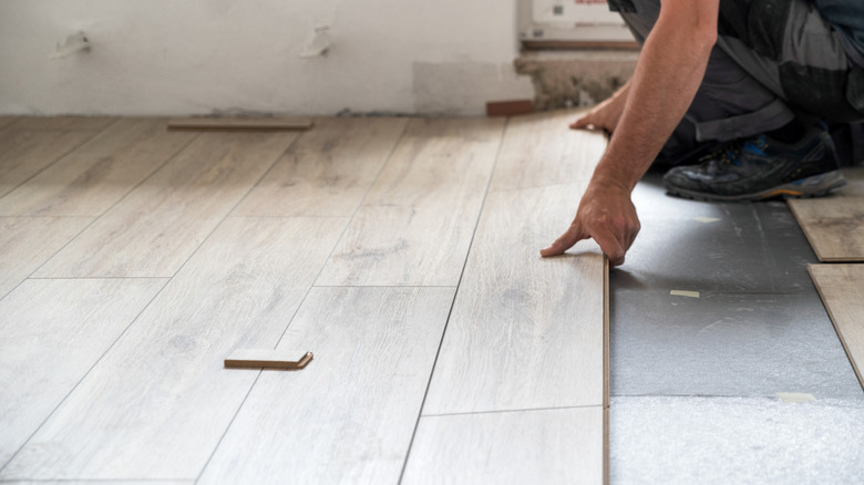 Man laying laminate flooring over an insulated base