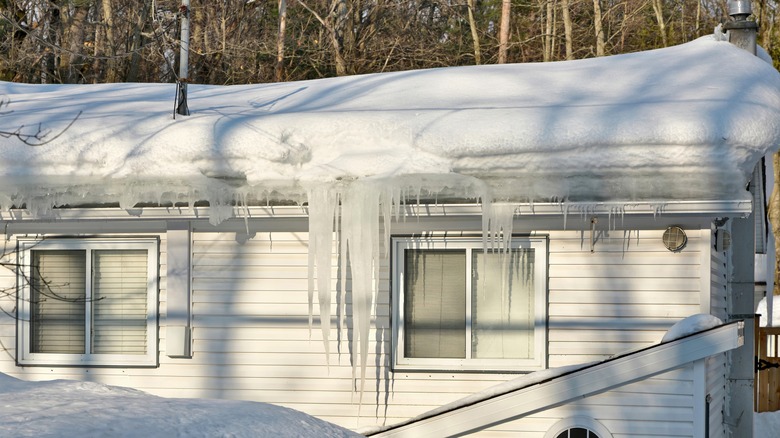 A white house with large icicles and ice dam in the gutters