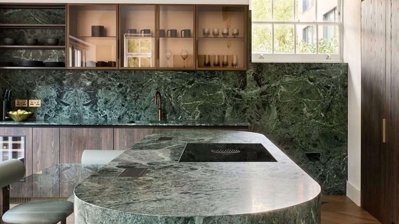 Stylish kitchen with warm wooden cabinets and bold Verde Alpi marble on backsplash, countertops, and kitchen island