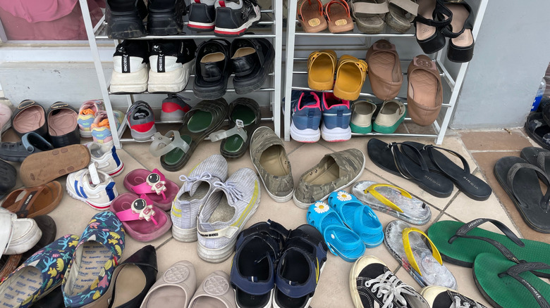 A messy pile of shoes on the floor of a room.