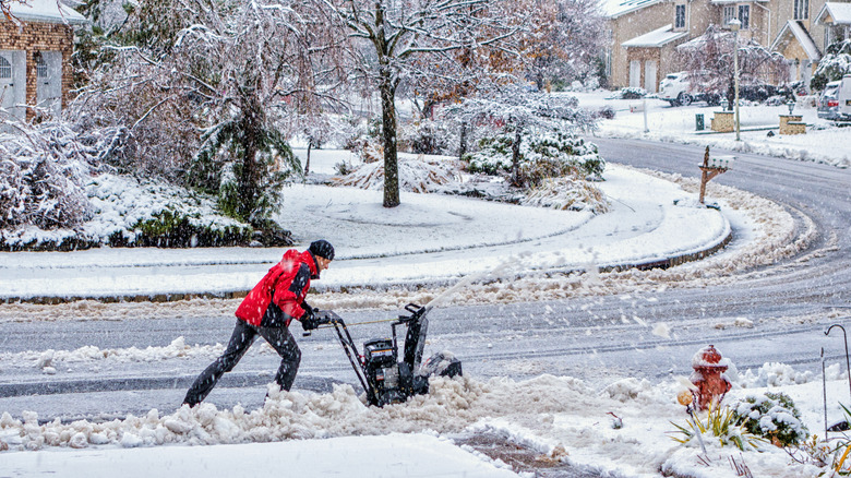 A man blows snow at the end of his driveway