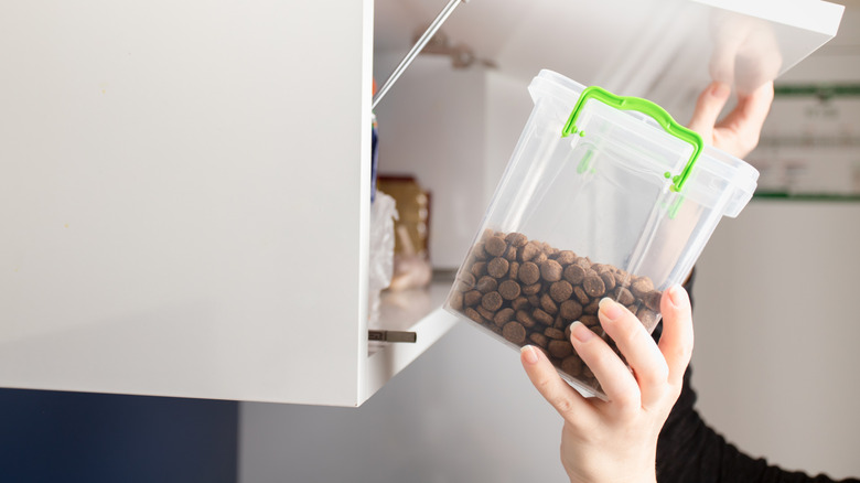 Close up of hand storing pet food  in separate cabinet