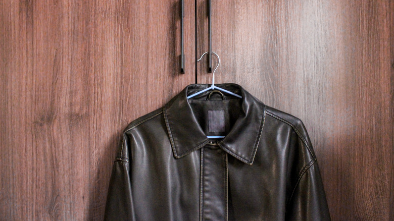 Black leather jacket hanging on the handle of a cabinet