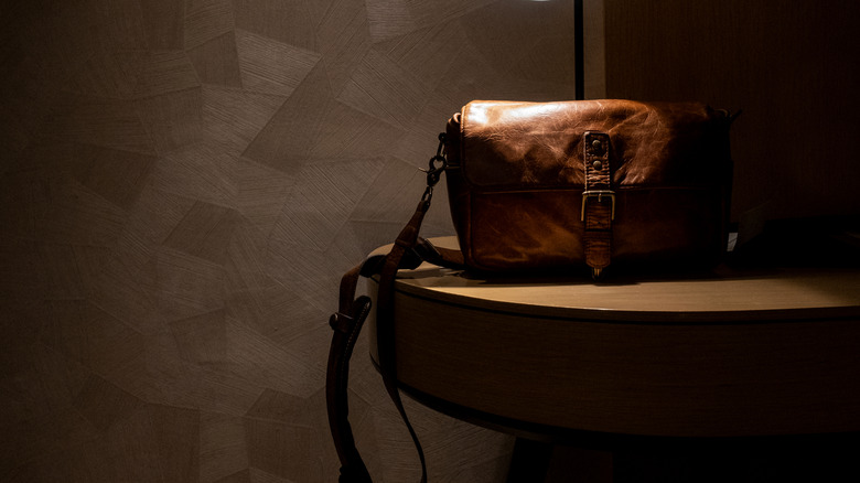 A leather bag placed in a dark spot in the room, away from the sunlight