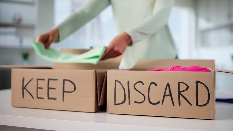 Person sorting belongings into "keep" and "discard" boxes