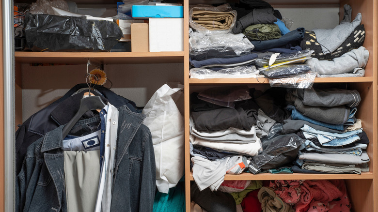 Cluttered closet, packed with messy trouses, jackets, and boxes