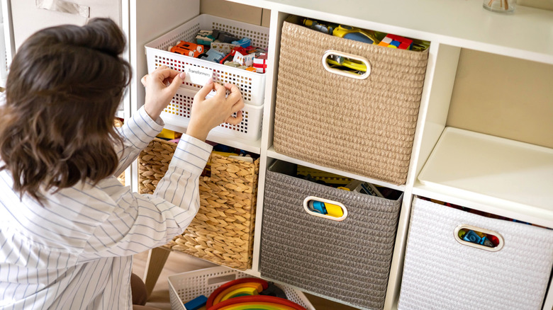 Woman organizes toys in baskets using cube storage.